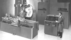 Early NC milling machine with operator at control console, representing a key stage in the history of CNC machines.