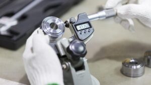 CNC Operator Responsibilities: What Every Operator Must Know 2 CNC operator responsibilities shown as digital micrometer measuring machined metal part during quality control inspection